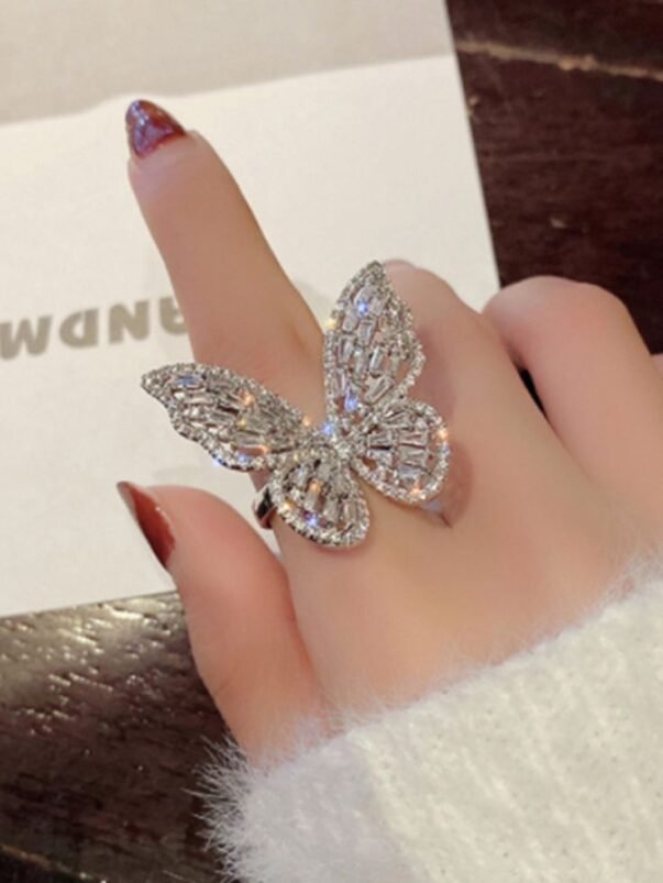 hand with red nail paint and butterfly diamond ring